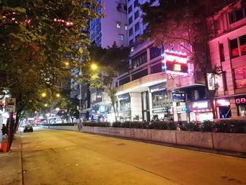 Illuminated street amidst buildings at night