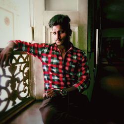 Young man looking away while sitting at home