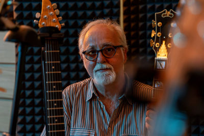 Middle-aged professional guitarist posing in his home recording studio amidst his guitar collection