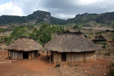 Thatched huts in village against sky