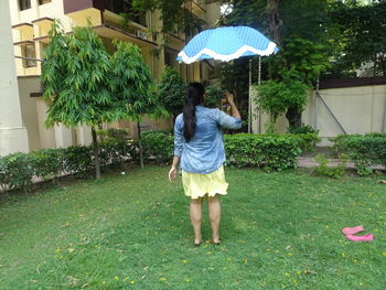 Rear view of woman standing in yard during rainy season