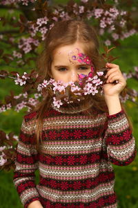 Spring portrait of a six year old girl standing under the blooming pink cherry tree