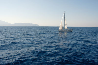 Sailboat sailing on sea against clear sky