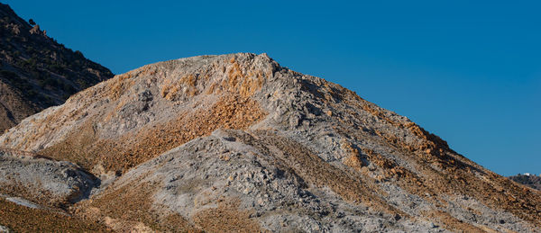 Low angle view of rocks against clear blue sky