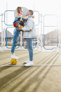 Couple hugging on a basketball court. girl on the basket ball. happy girlfriend and boyfriend