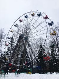 Low angle view of ferris wheel against sky during winter