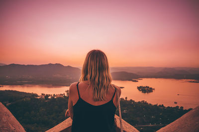 Woman looking at sea against sky during sunset