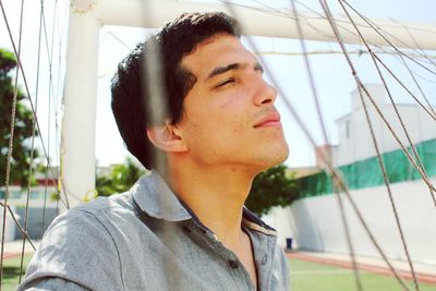 Close-up of young man with eyes closed seen through goal post