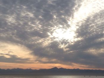 River by mountains against cloudy sky during sunset