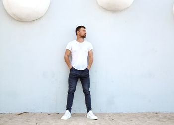 Full length of young man standing against white wall