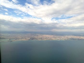 Aerial view of city by sea against sky