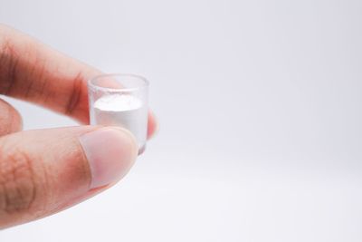 Close-up of hand holding glass against white background