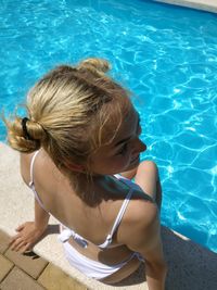 High angle view of teenage girl sitting by swimming pool during summer