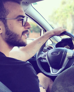 Side view of young man sitting on car