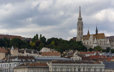 View of buildings in town against cloudy sky