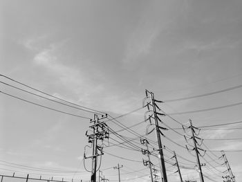 Low angle view of electricity pylons against sky