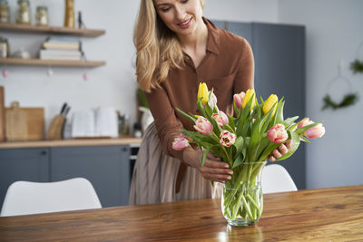Midsection of woman with flowers on table