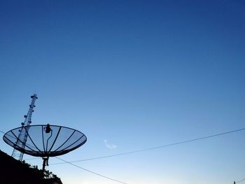 Low angle view of electricity pylon against clear blue sky