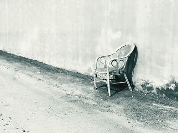 Empty bench on road against wall in city