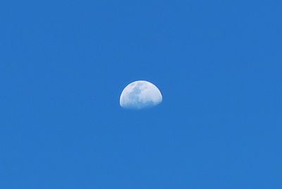 Low angle view of moon against clear blue sky