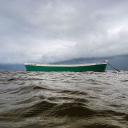 Boats in sea against cloudy sky