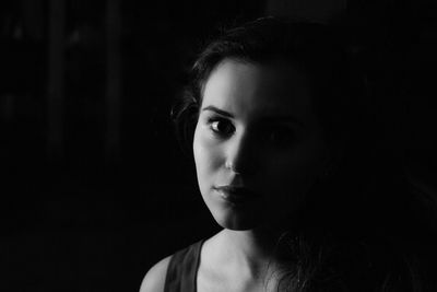 Close-up portrait of a beautiful young woman over black background