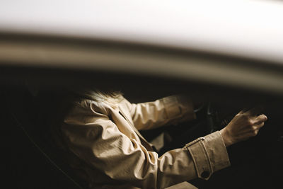 Midsection of businesswoman sitting on driver's seat in car