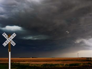 Railroad crossing and landscape against storm clouds