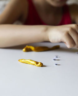 Midsection of girl playing with yellow clay on table