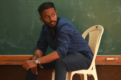 Young man looking away while sitting on chair