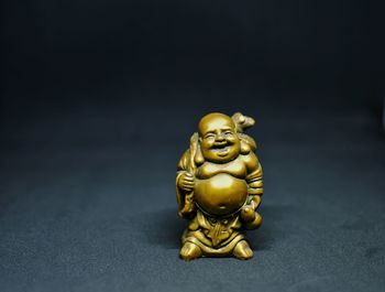 Close-up of buddha statue on table against black background