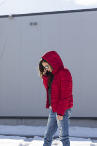 Woman with red umbrella standing in snow