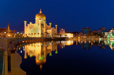 Reflection of illuminated mosque on lake city at night