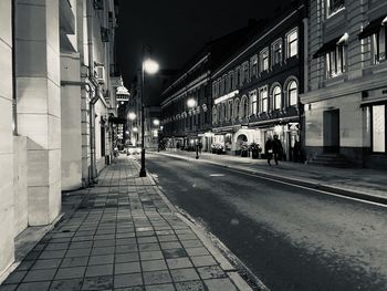 Illuminated street amidst buildings in city at night