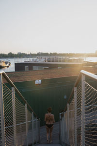 Rear view of woman standing by swimming pool against sky
