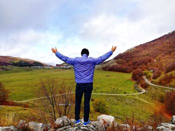 Man from behind with open arms enjoys nature in solitude