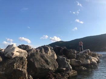 Man standing on rock against sky