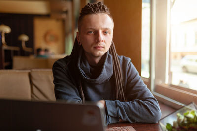 Portrait of young man using mobile phone at home