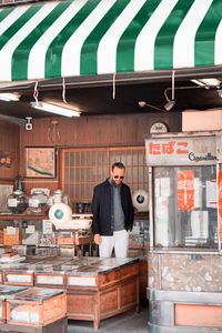 Full length portrait of young man standing at cafe