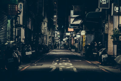 Illuminated street amidst buildings in city at night