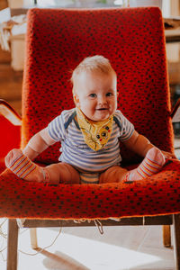 Portrait of cute baby boy sitting on sofa at home