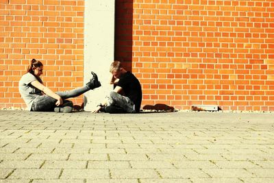 Young couple sitting on brick wall