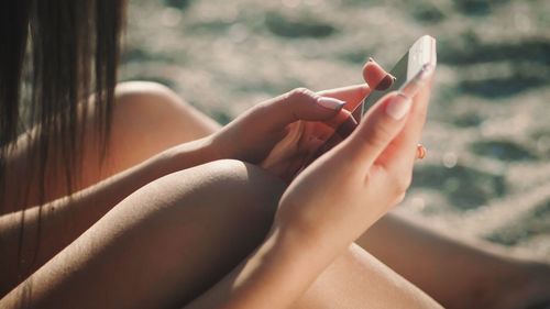 Low section of woman holding smart phone