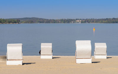 Deck chairs on beach against clear blue sky
