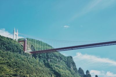 Low angle view of suspension bridge against blue sky