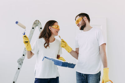 Happy smiling married couple engaged in renovation repair in the room of the house preparing to move