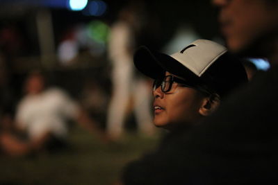 Close-up of man and girl looking away on land at night