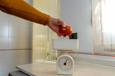 Midsection of man holding clock at home