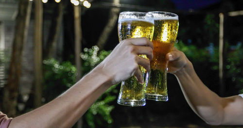 Cropped hands of friends toasting beer glasses