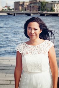 Portrait of smiling young woman standing against sea